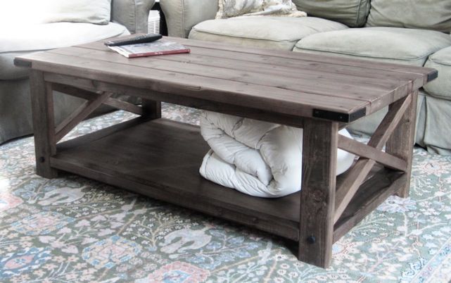 A wooden coffee table with a blanket underneath it in a living room
