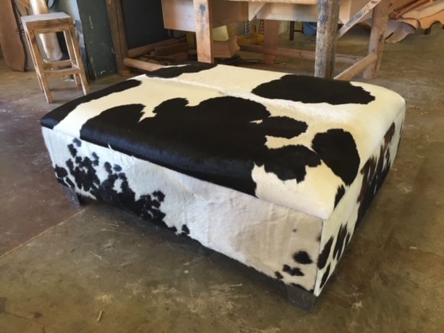 A black and white cow print ottoman is sitting on the floor