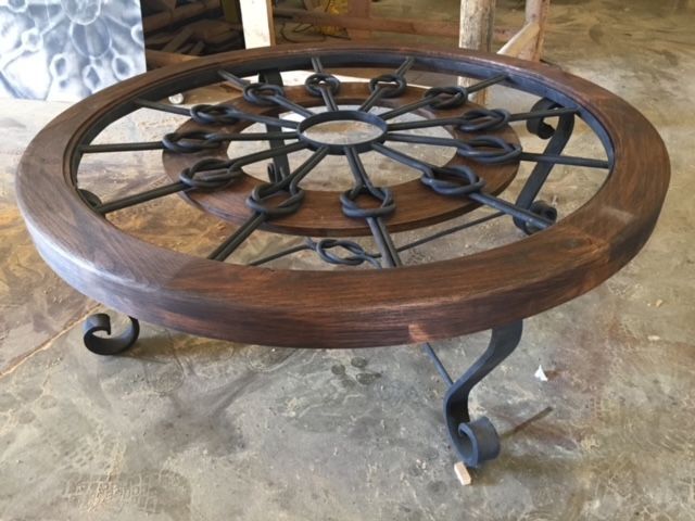 A wooden table with a wrought iron wheel on top