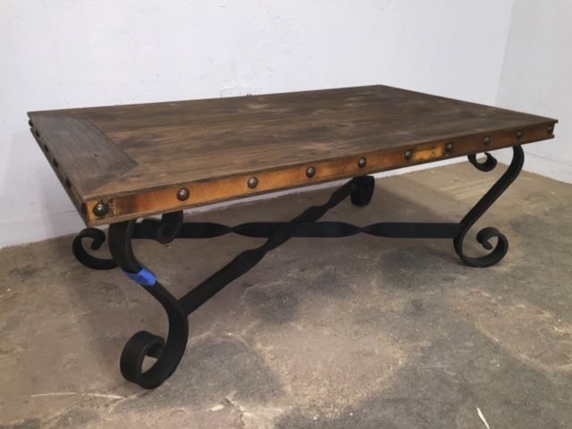 A coffee table with a wooden top and wrought iron legs