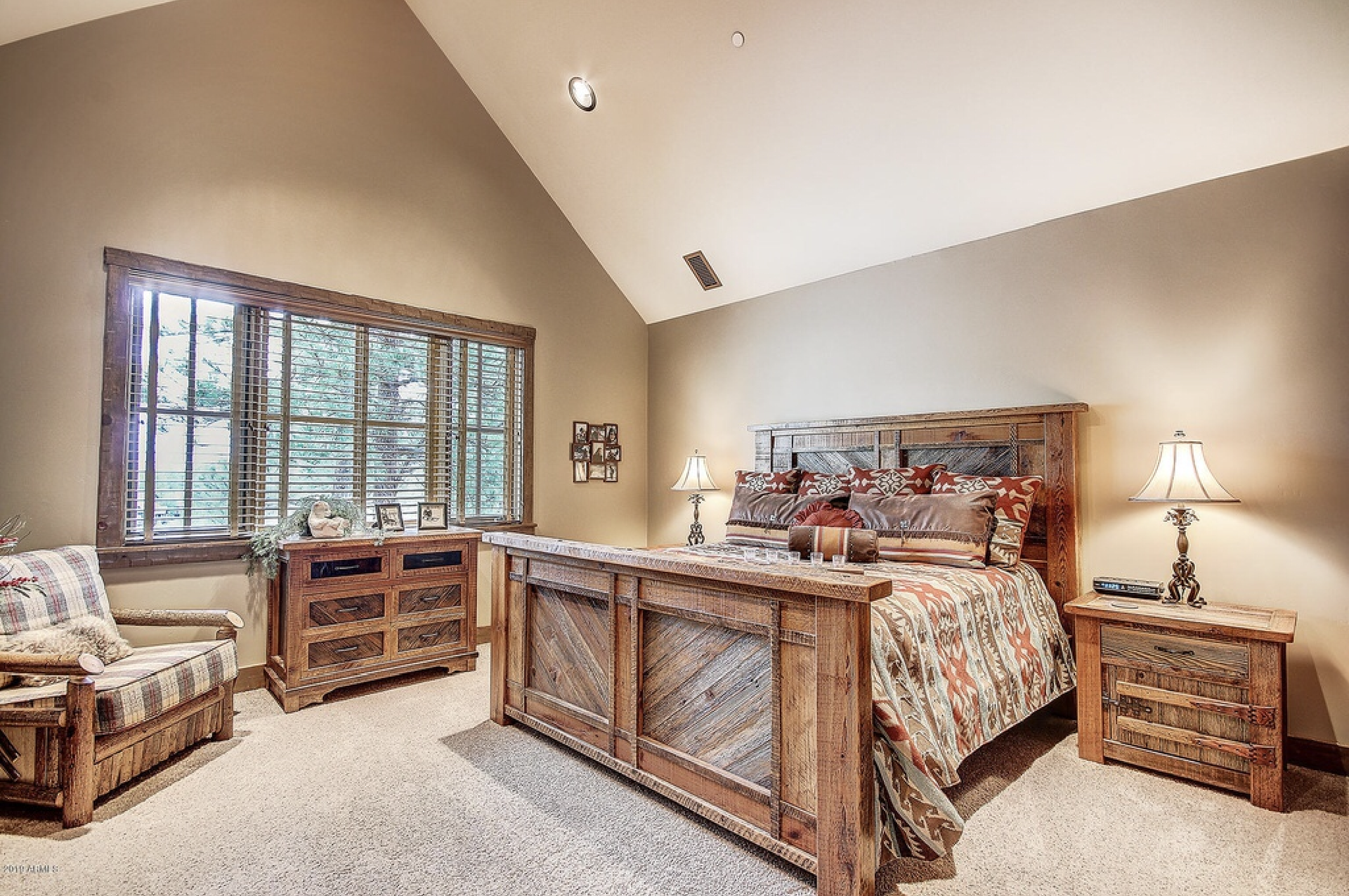 a bedroom with a king size bed , dresser , nightstand , chair and lamps