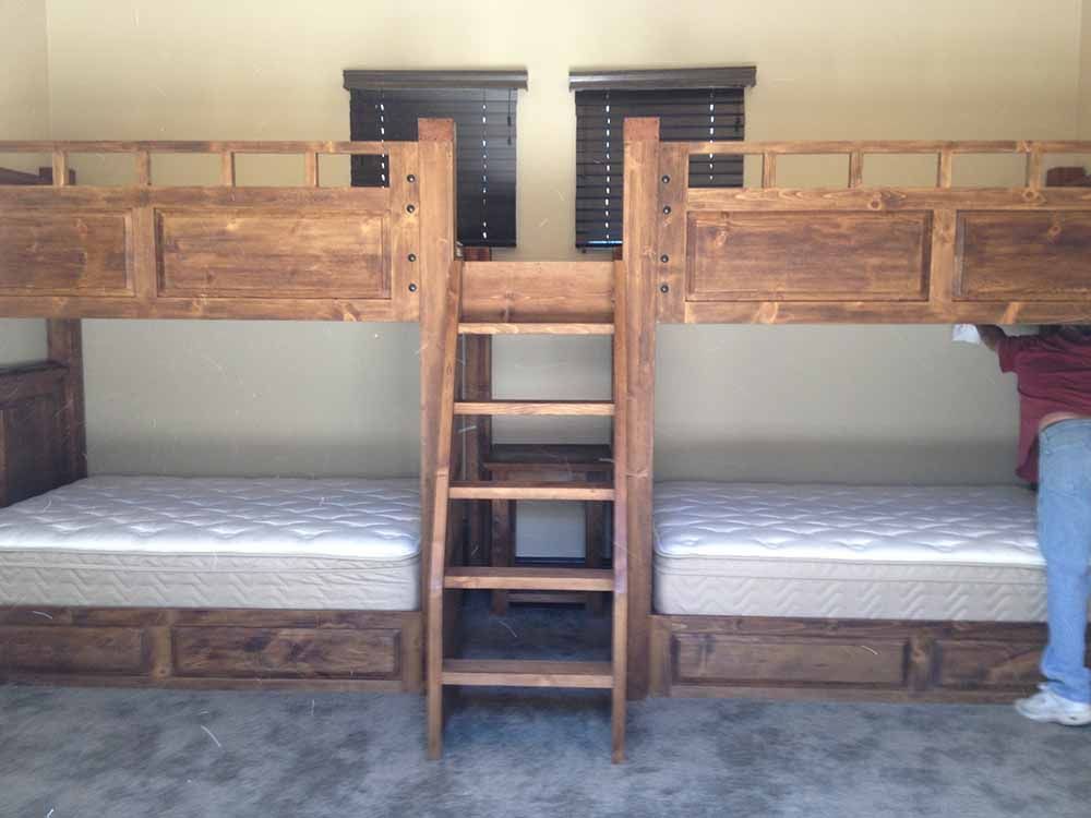 a person is standing in a room with bunk beds and a ladder