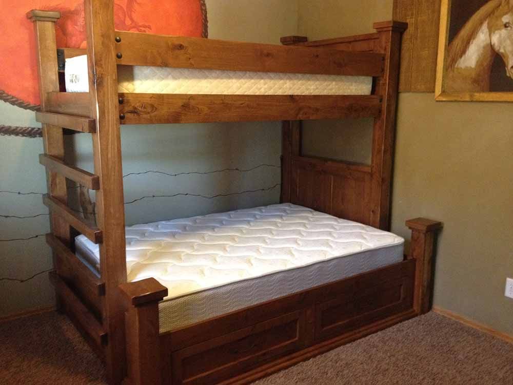 a bunk bed with a mattress in a bedroom with a picture of a horse on the wall