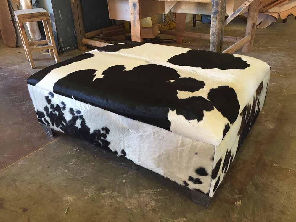 a black and white cow print ottoman is sitting on a concrete floor
