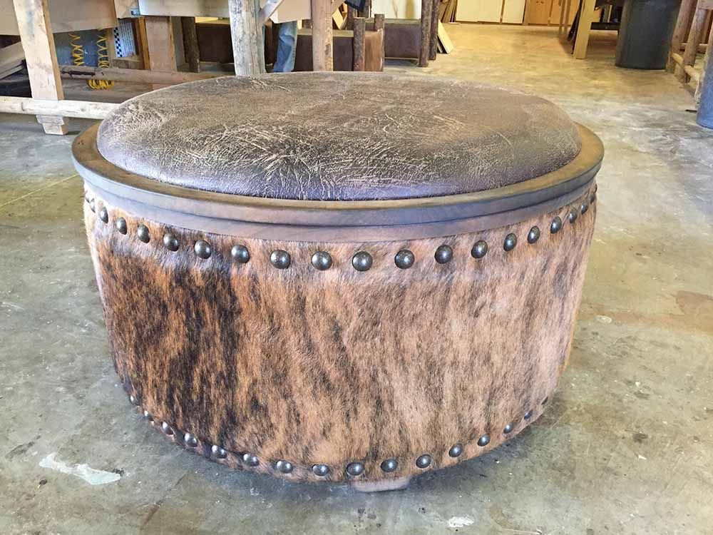 a brown ottoman with studs on it is sitting on a concrete floor