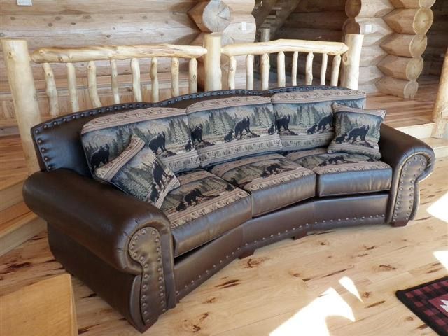 a couch in a log cabin with a staircase in the background