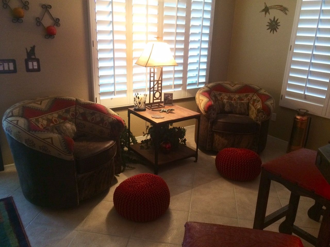 a living room with two chairs a table and a lamp
