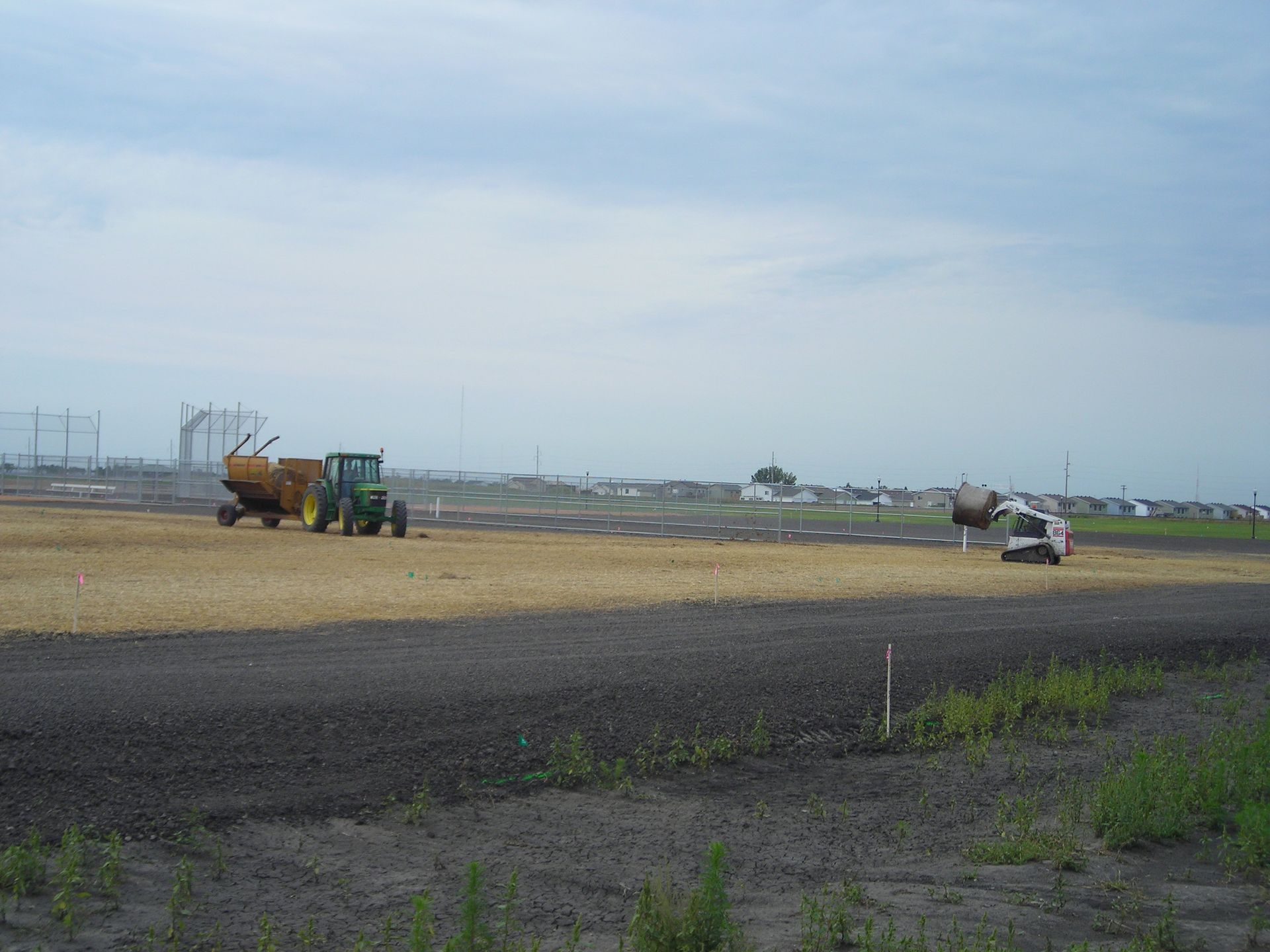 A tractor is plowing a field with a truck in the background.