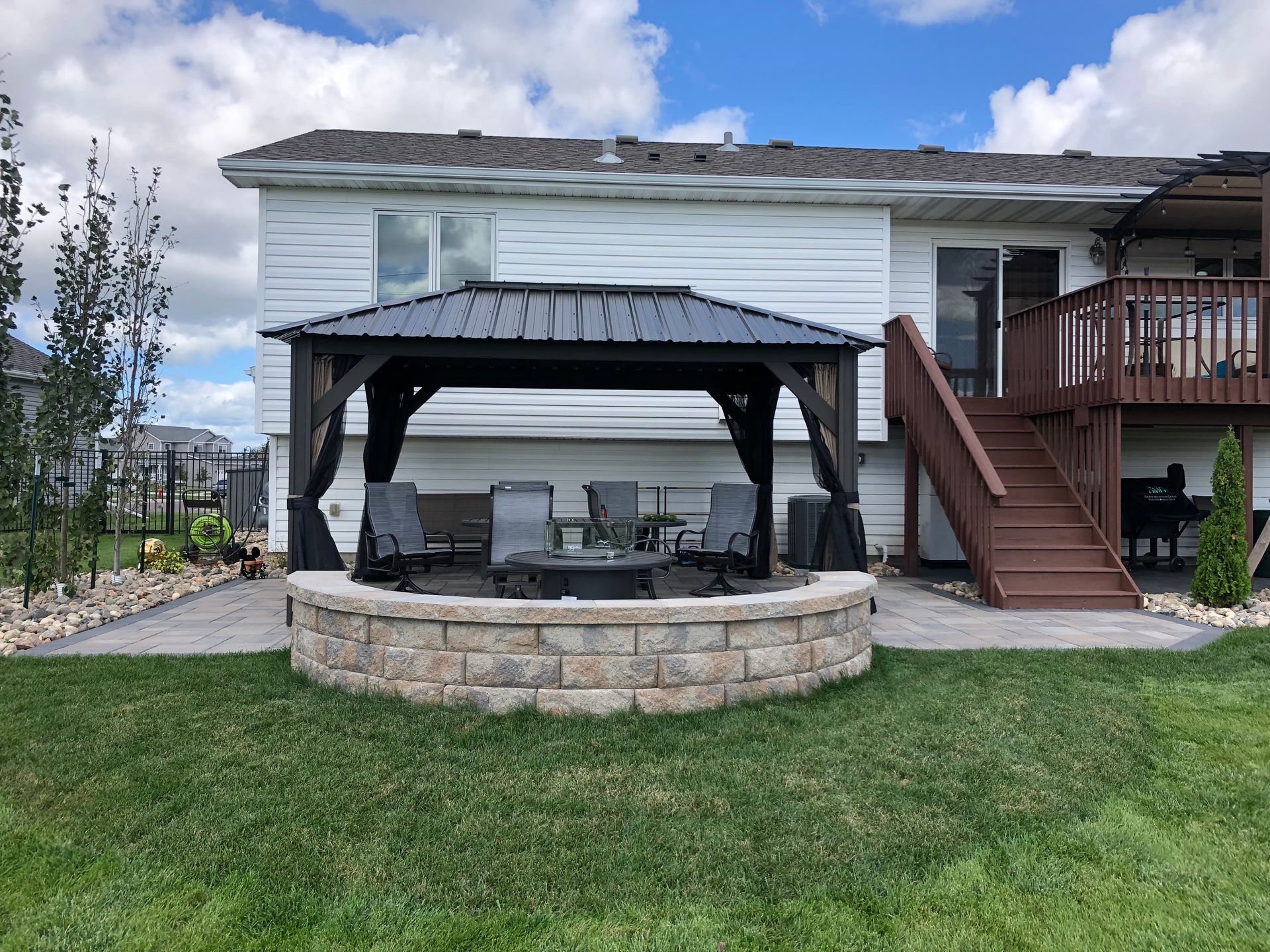 A gazebo with a fire pit in the backyard of a house.