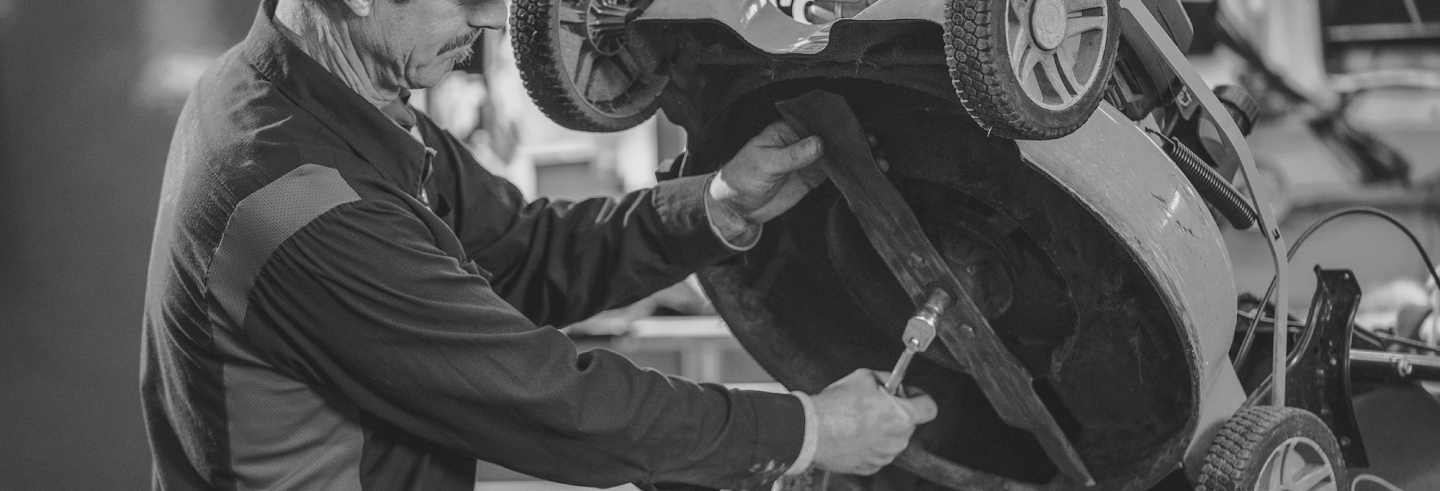 A black and white photo of a man working on a car.