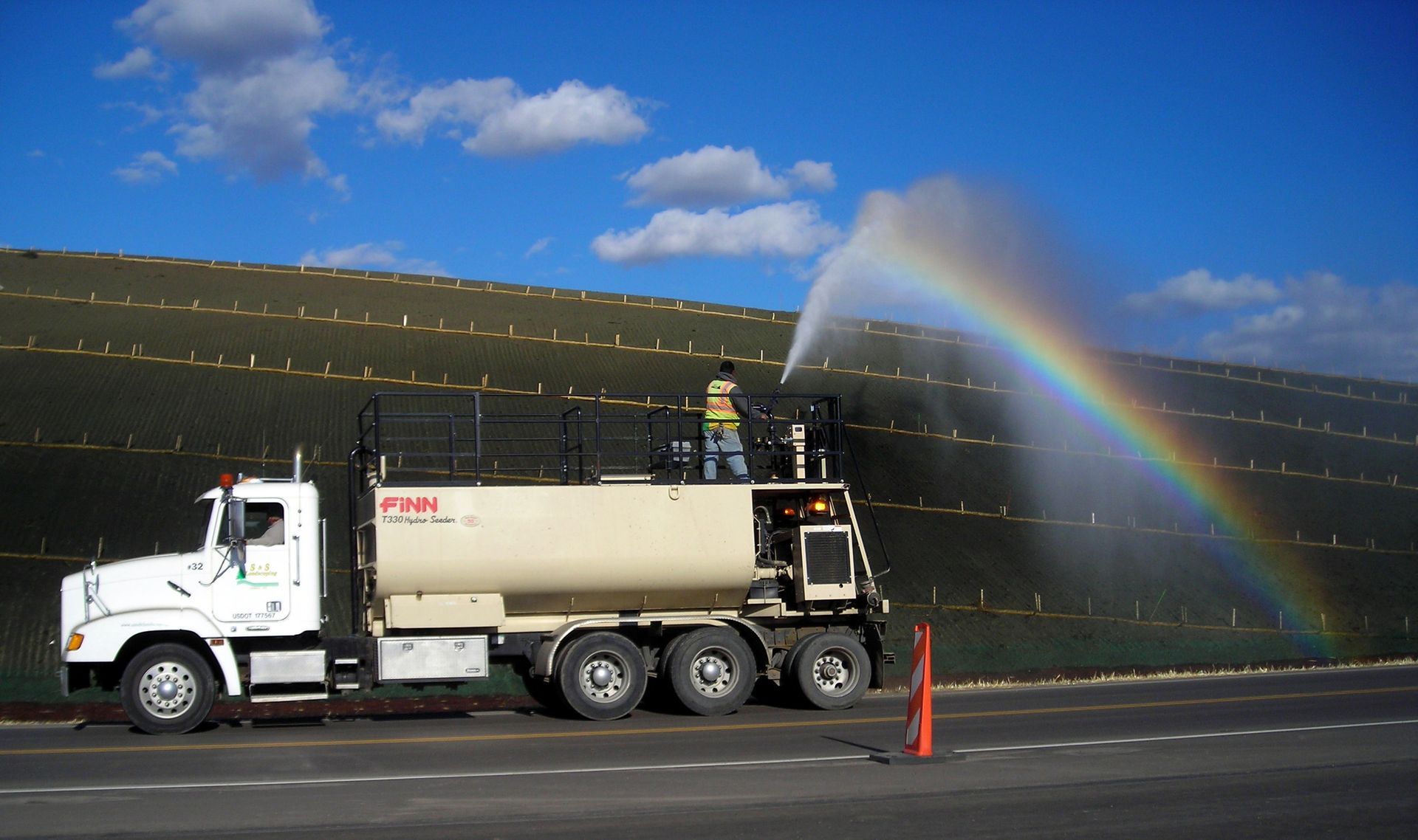 A truck spraying water with a rainbow in the background
