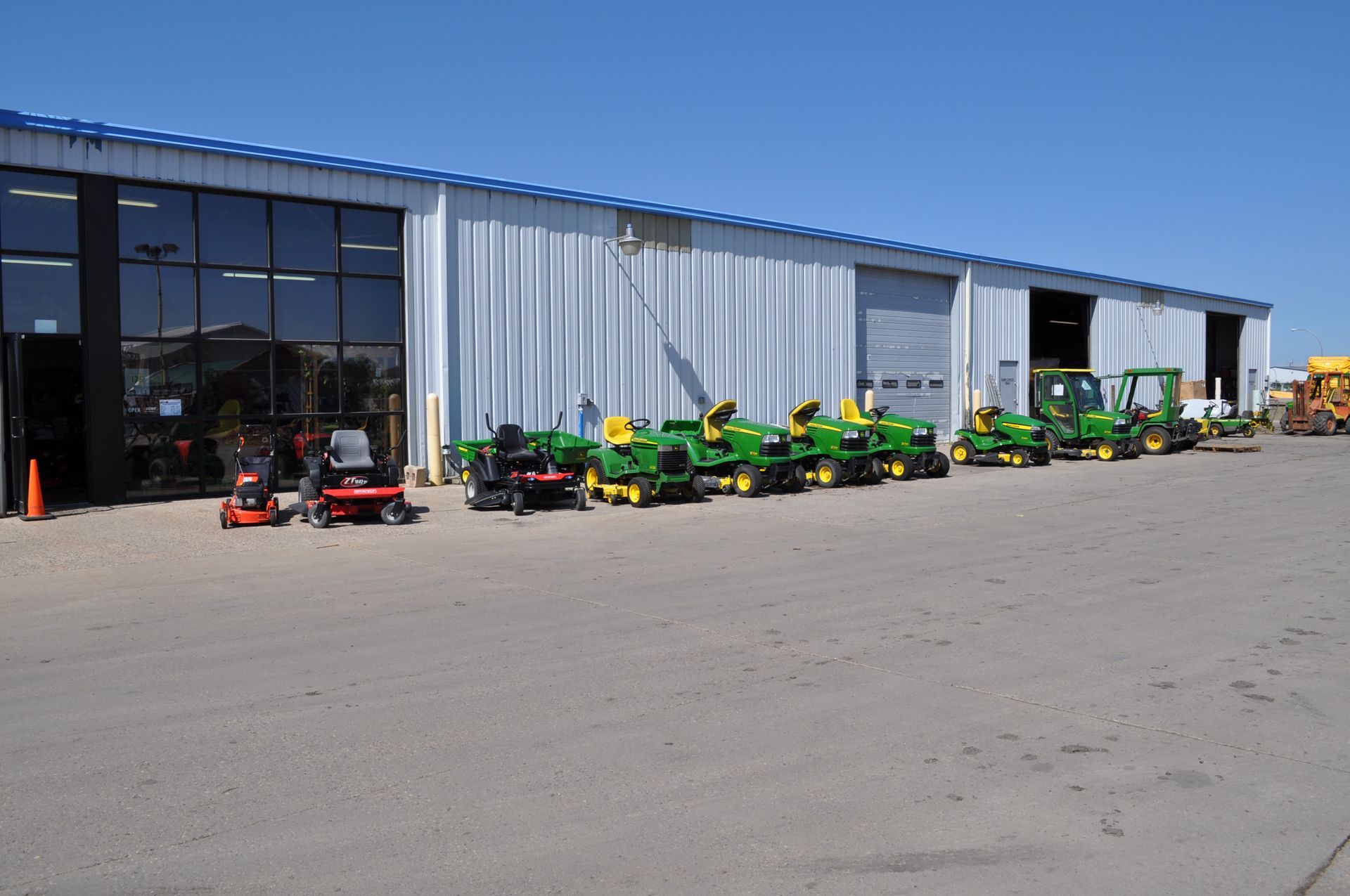 A row of john deere lawn mowers are parked in front of a building