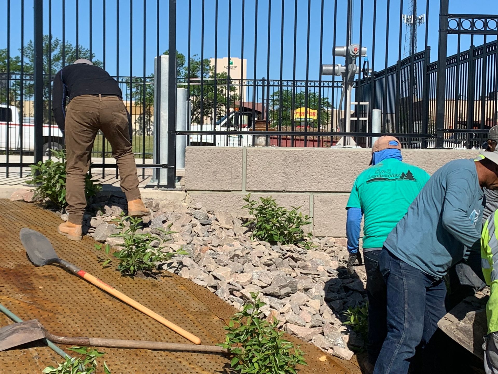 A group of people are working on a project in front of a fence.