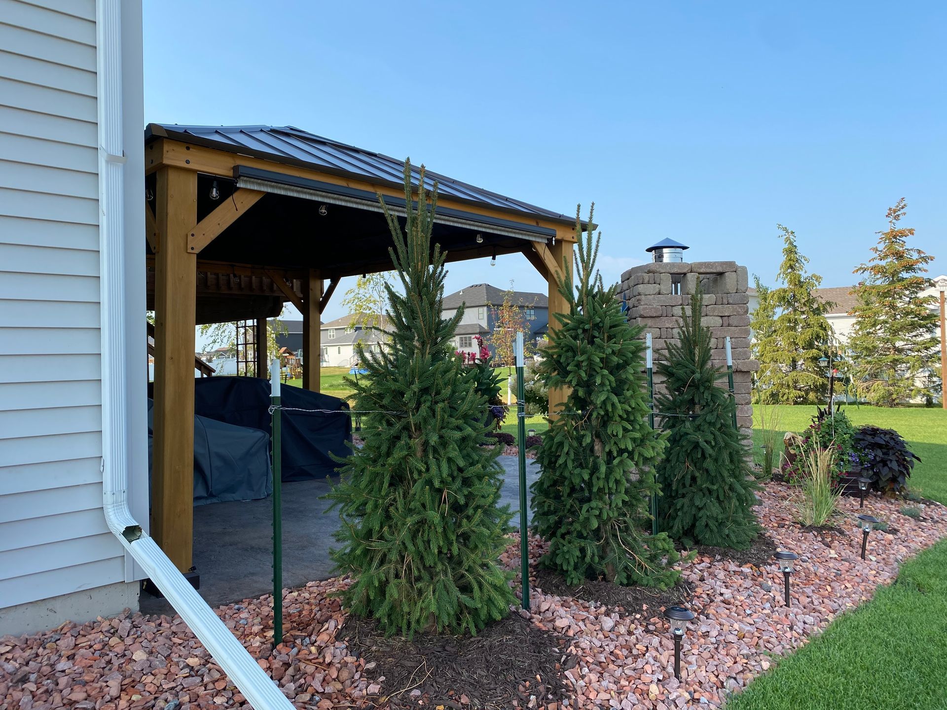 A white house with a gazebo and trees in front of it.