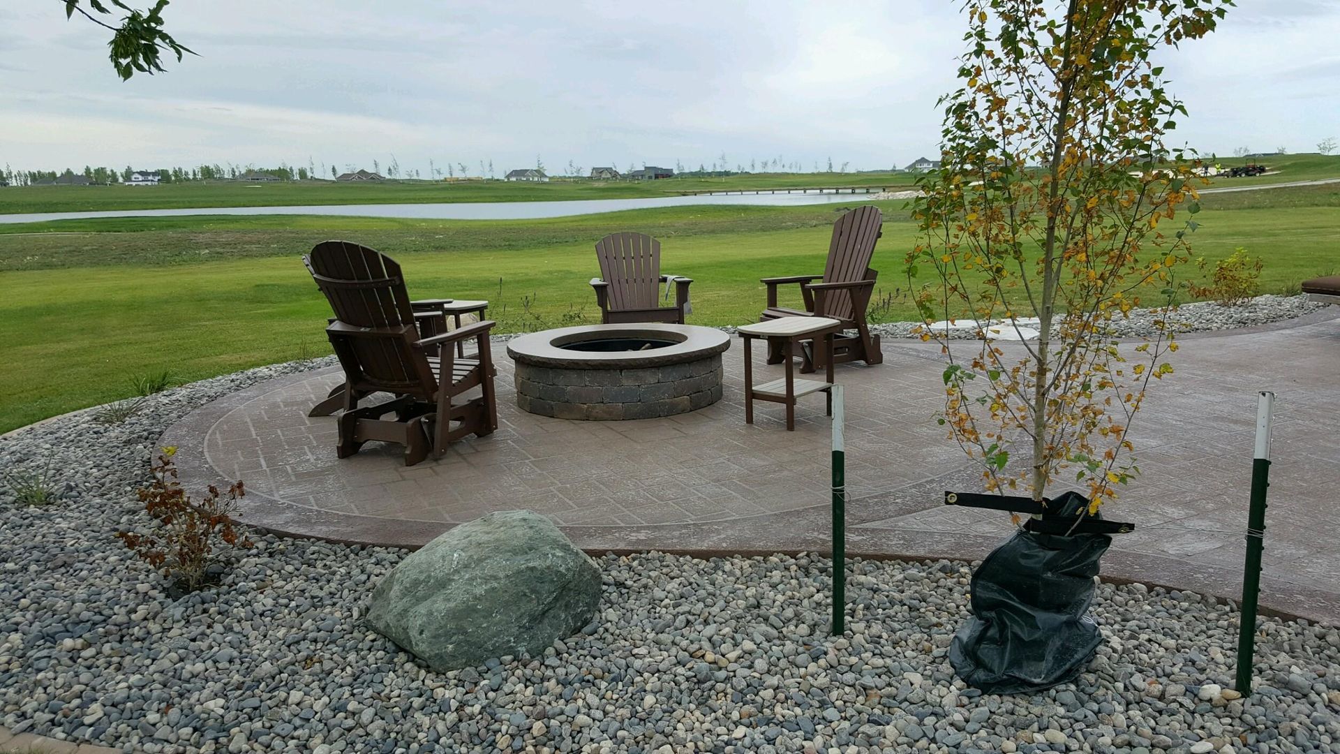 A fire pit is surrounded by rocks and chairs
