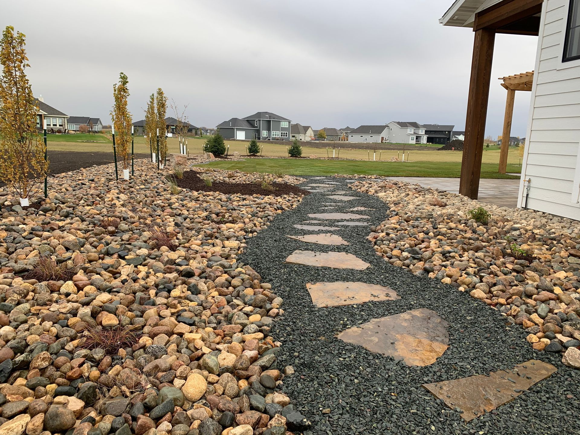 A stone walkway leading to a house surrounded by rocks and gravel.