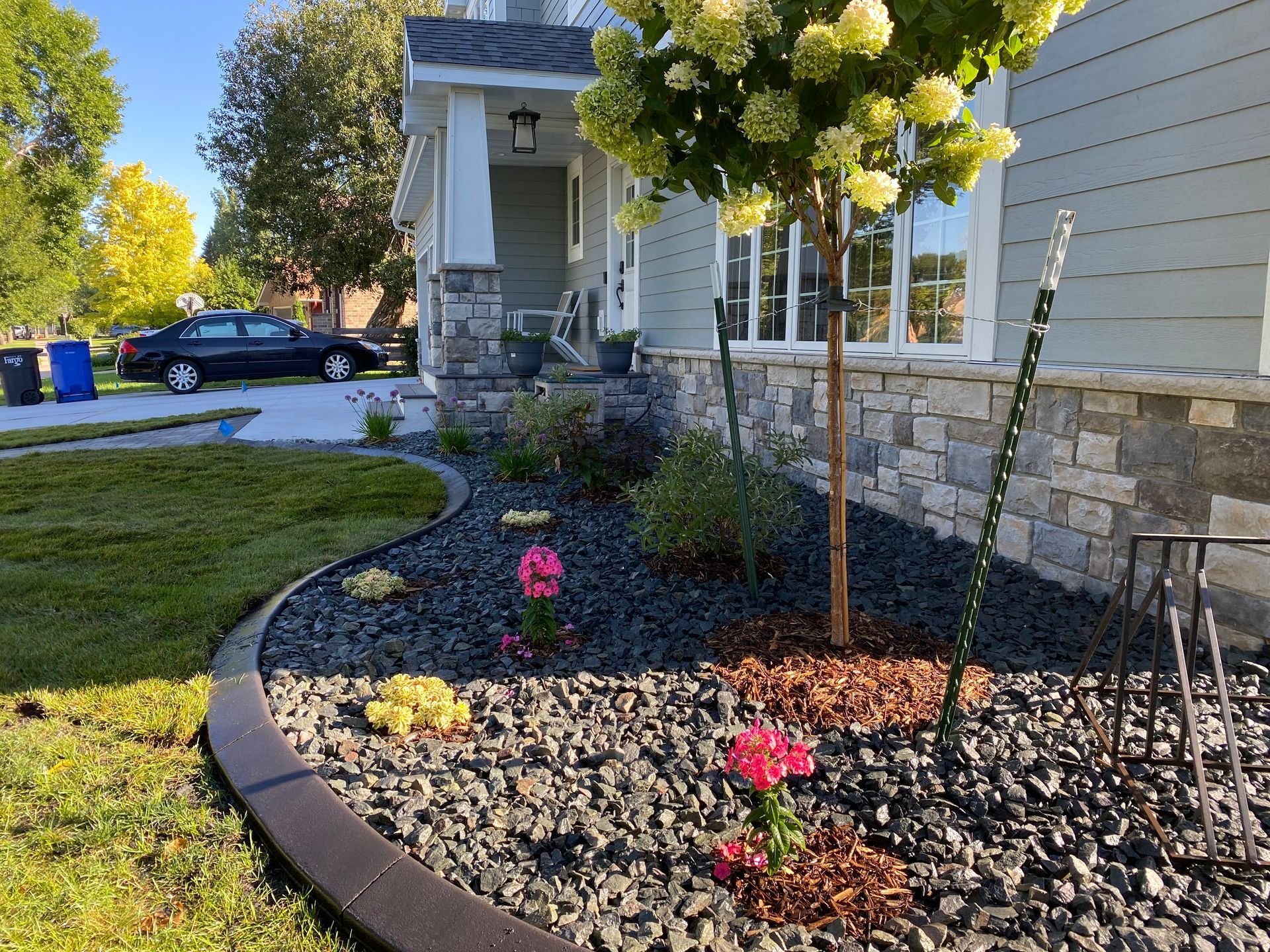 A garden with flowers and rocks in front of a house.