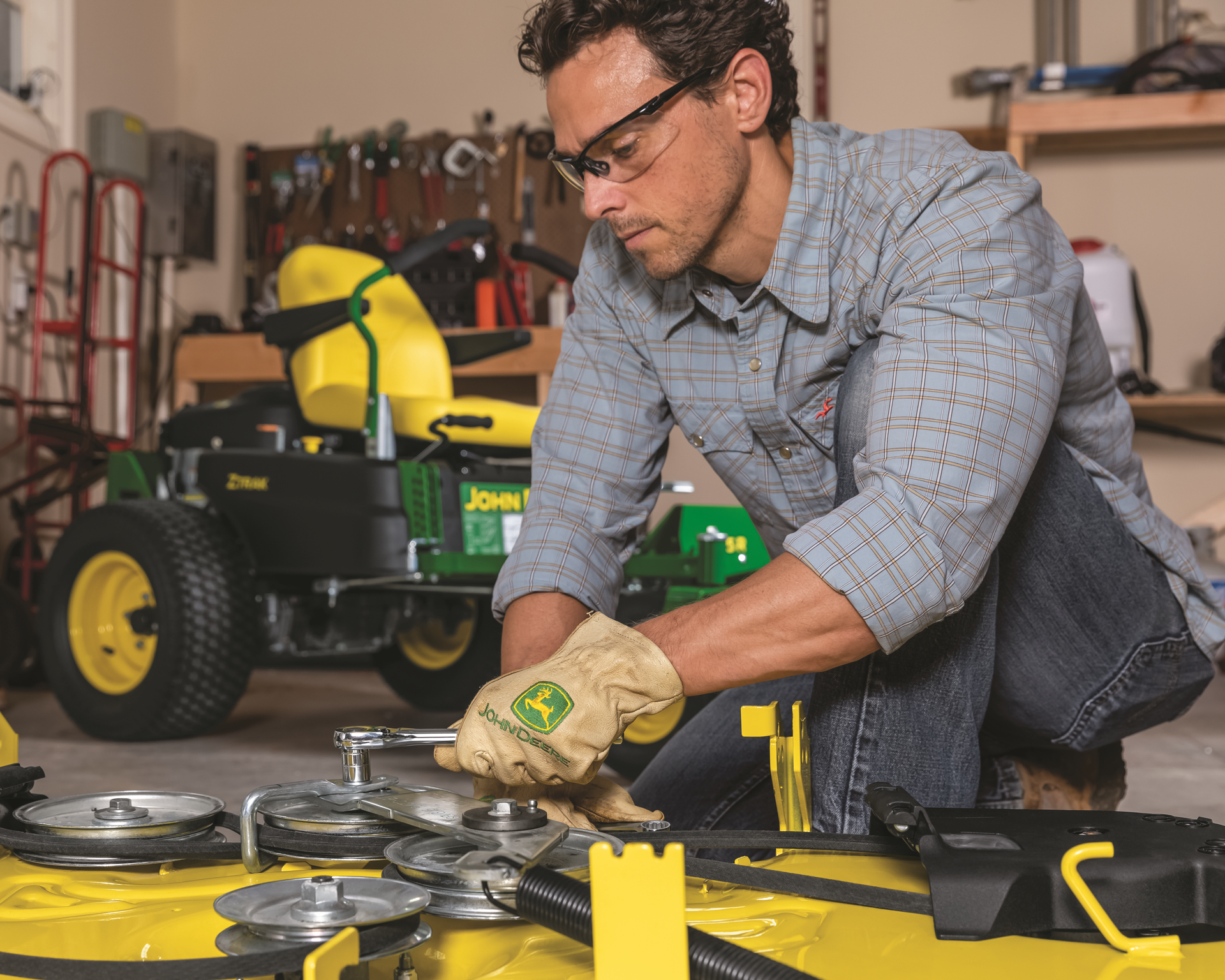 A man is working on a john deere lawn mower in a garage