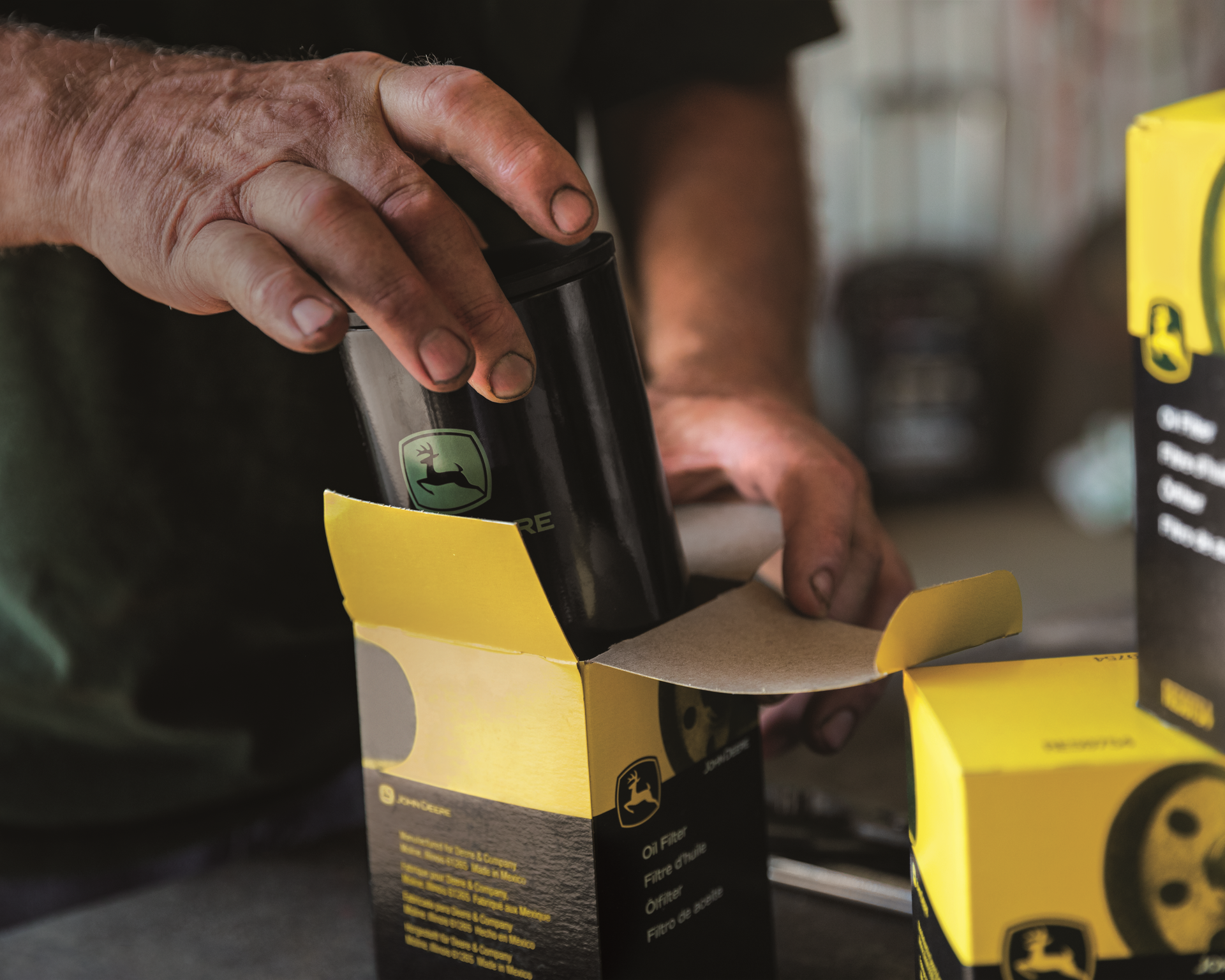 A man is opening a box of john deere parts.