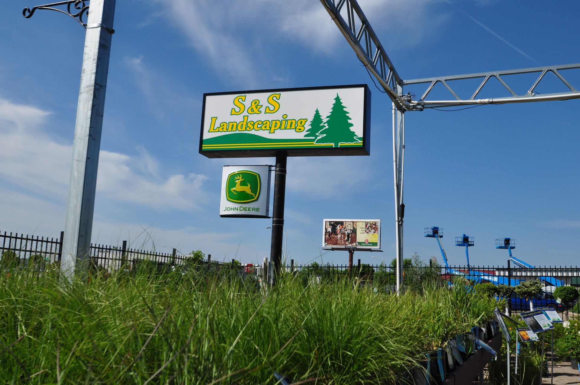 A sign for s & s landscaping with a john deere logo