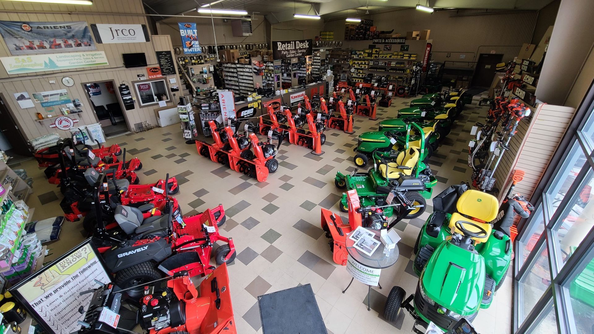 A large room filled with lots of lawn mowers and tractors.