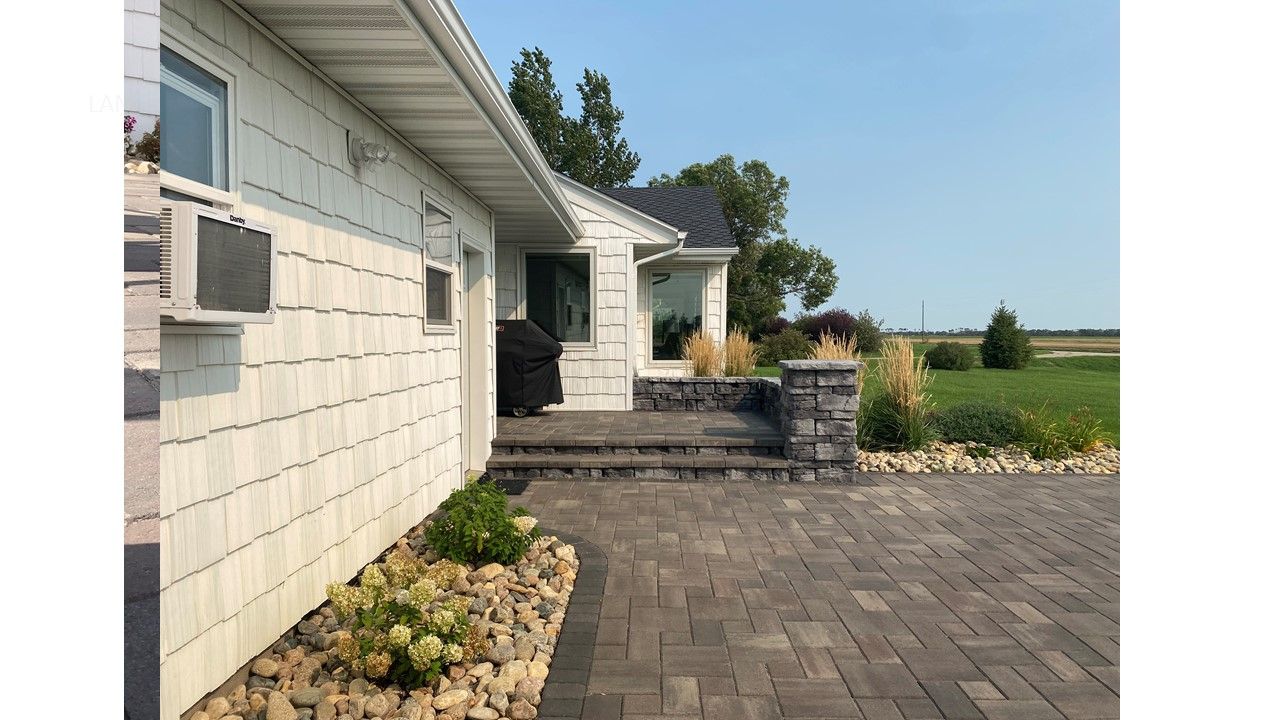 A white house with a brick driveway in front of it.