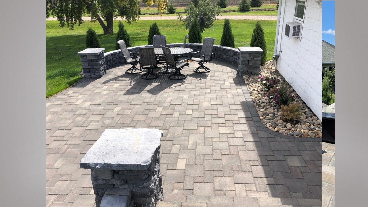 A patio with a table and chairs on it in front of a house.