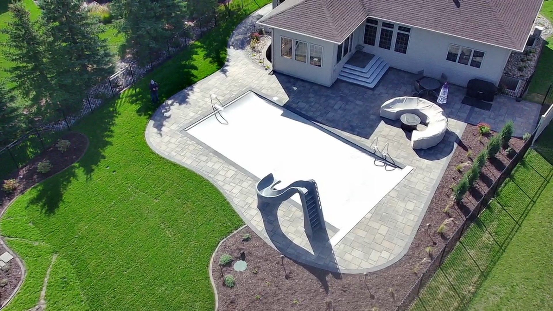 An aerial view of a house with a large swimming pool in the backyard.