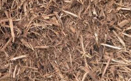 A pile of brown mulch is sitting on the ground.