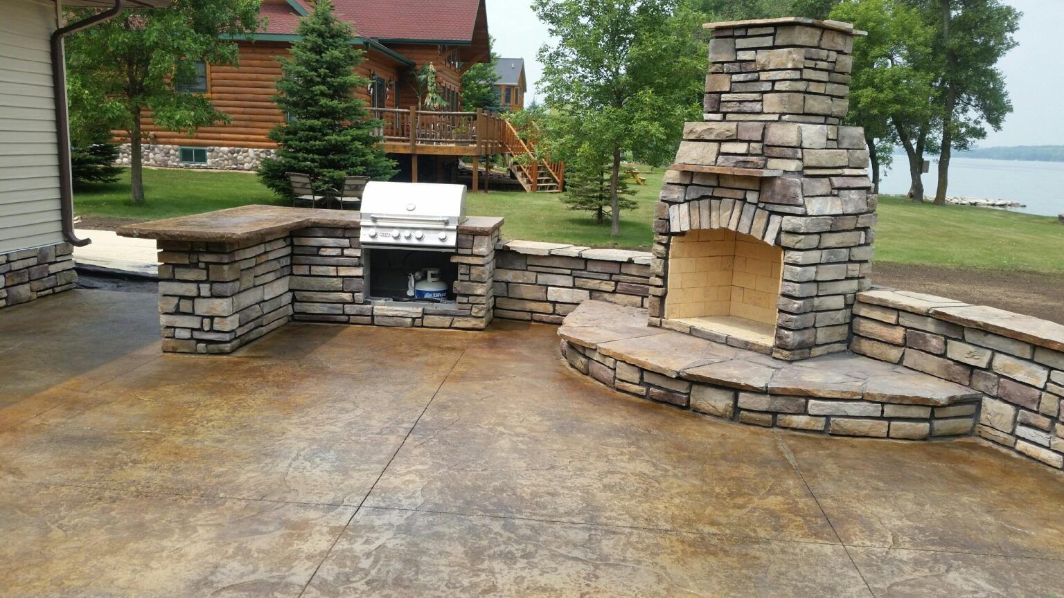 A patio with a fireplace and a grill in front of a house.