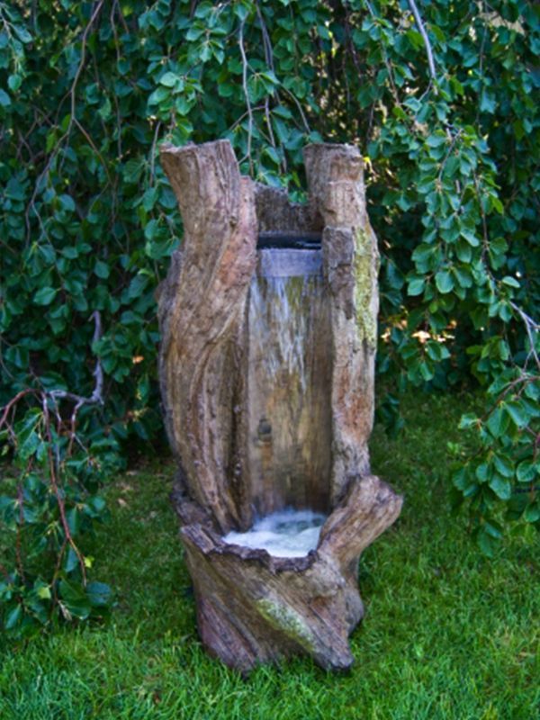 Water fountain in the shape of a tree trunk, water flowing down into a pool of water, set in a grassy garden.