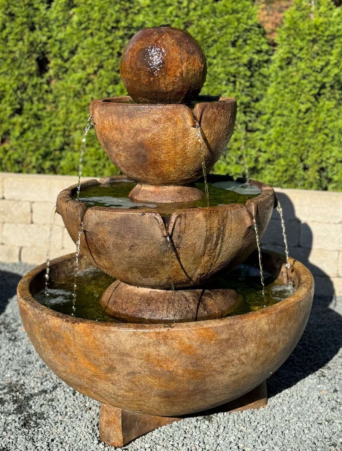 Stone tiered outdoor fountain with water flowing down.
