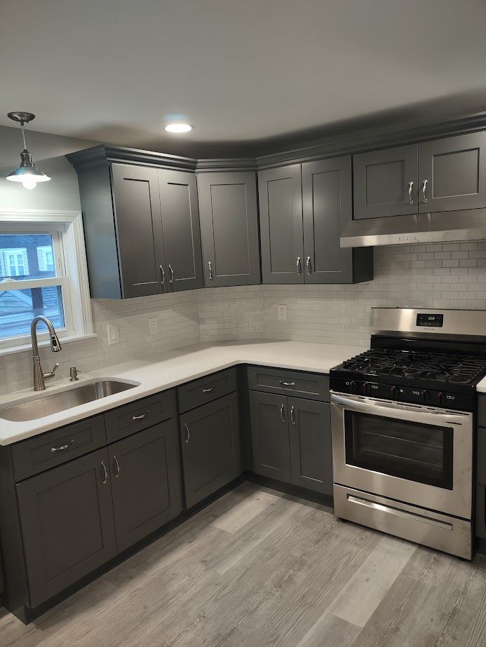 Gray kitchen with cabinets, stainless steel appliances, and white countertops.