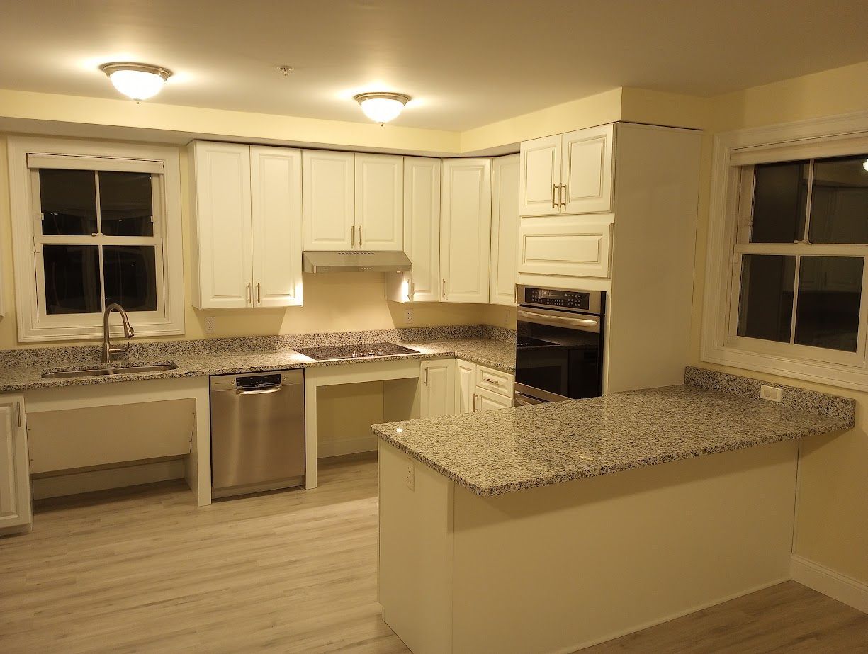 White kitchen with granite countertops, light wood-look floor, and accessible sink area.