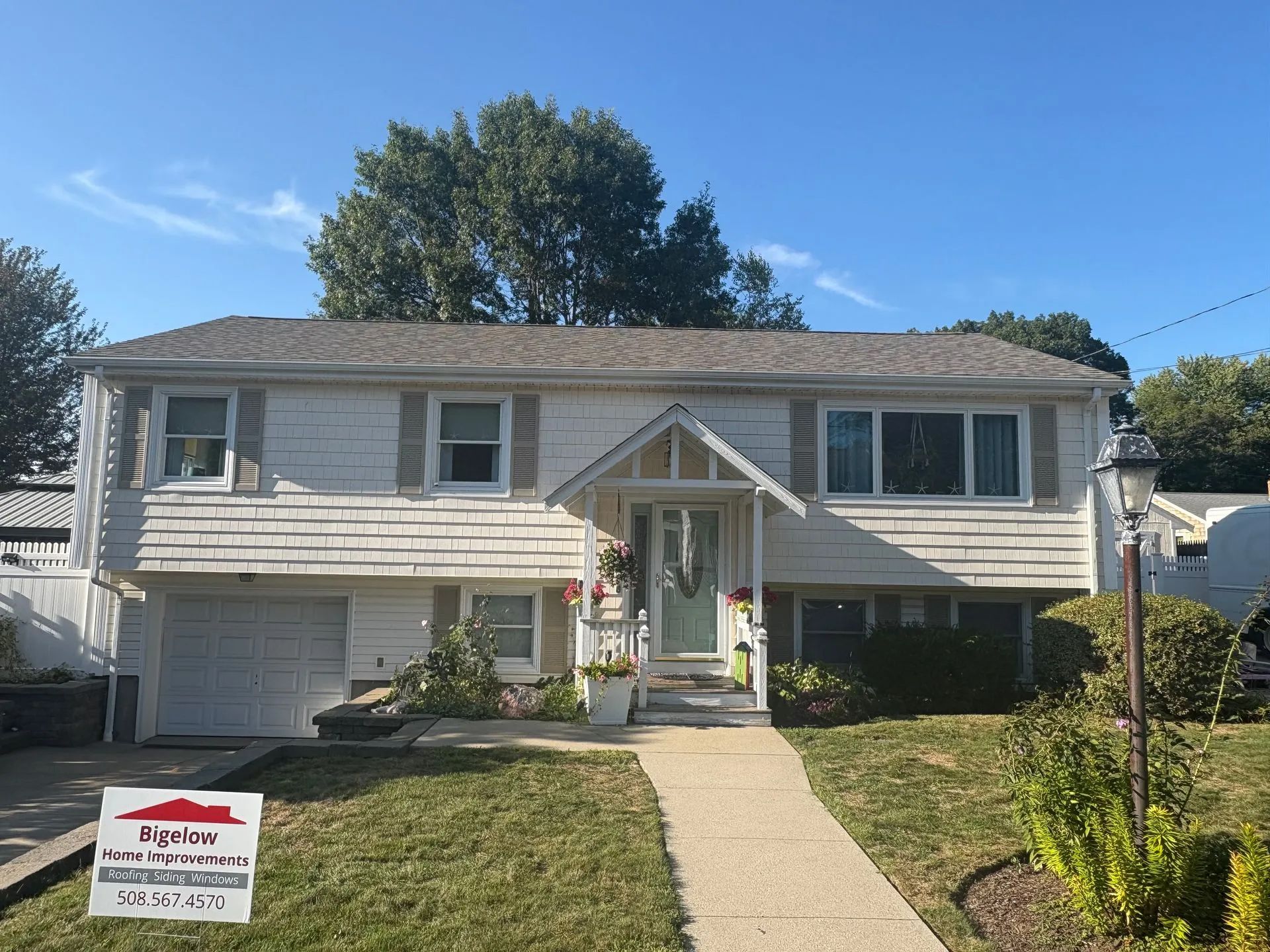 White house with a gray roof and windows on a sunny day. A walkway leads to the front door.