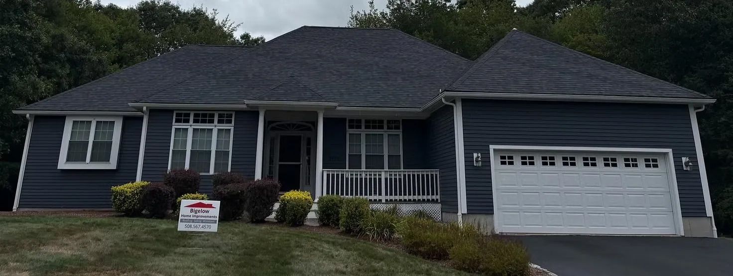 A blue house with a white garage door, and a sign in the front yard.