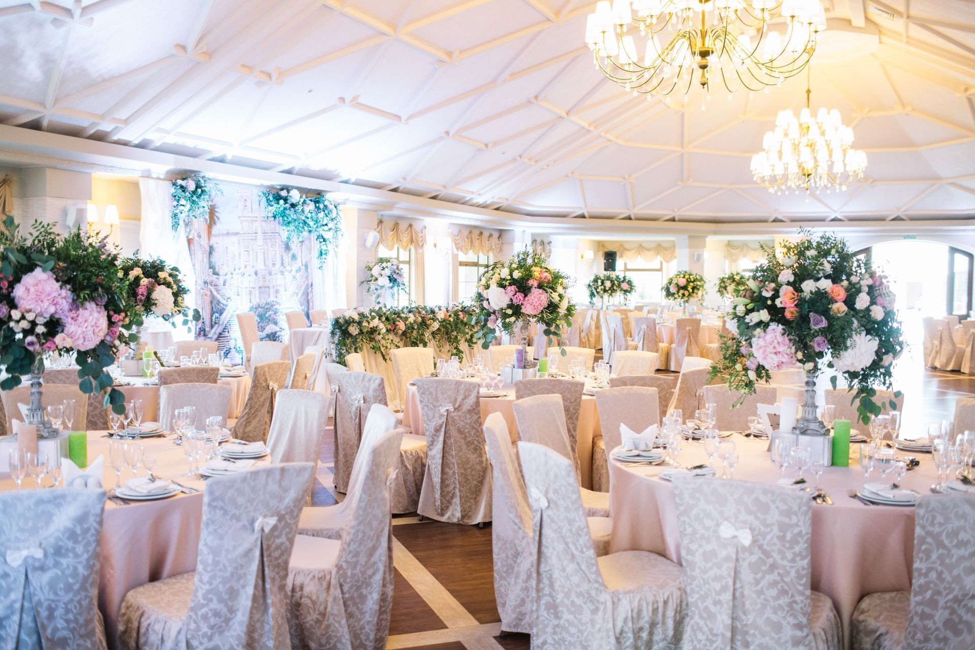 Elegant banquet hall set for a wedding reception with white and blush table settings and floral centerpieces