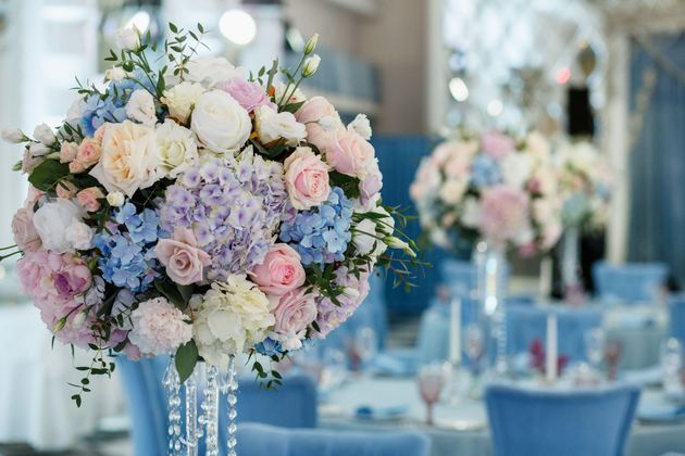 Pastel floral centerpieces on blue tables in a decorated banquet hall