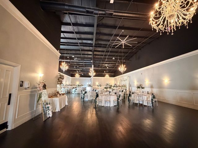 Elegant banquet hall with round tables, white chairs, and chandeliers under a dark ceiling