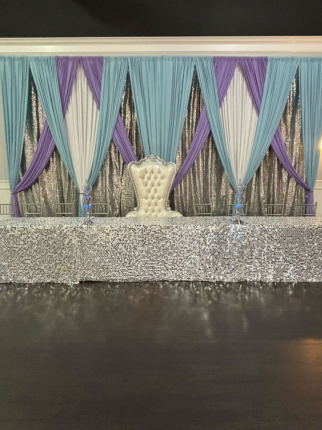 Decorative beaded curtain with blue, purple, and white triangular panels above a silver tabletop or stage ledge