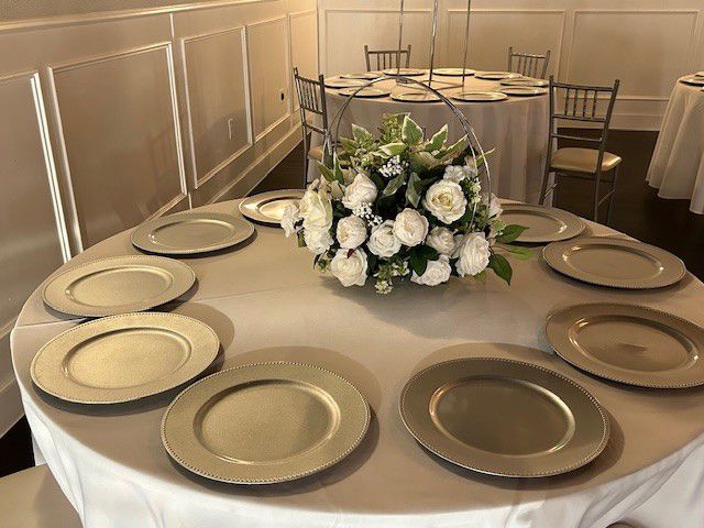 Round banquet table set with beige plates and a white floral centerpiece in a formal dining room
