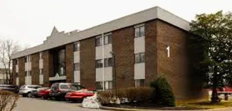 Brick apartment building with parked cars and a large white 