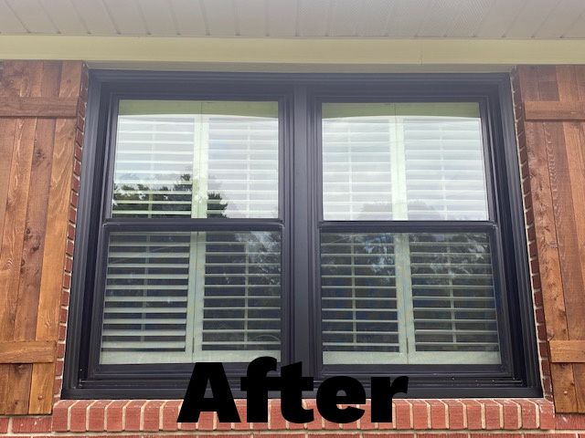 Double-pane window with black frame and light-colored blinds; wooden shutters on red brick house.