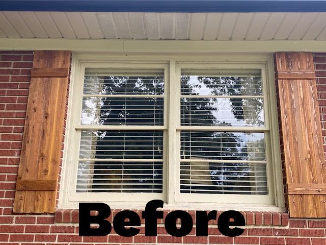Brick building with a double window, beige trim, and wooden shutters. 