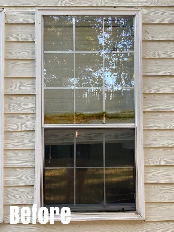 Before image of a white window on beige siding. The top portion has clear glass, the bottom is dark.