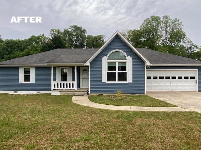 Blue house with white trim, garage, and arched window under a cloudy sky.