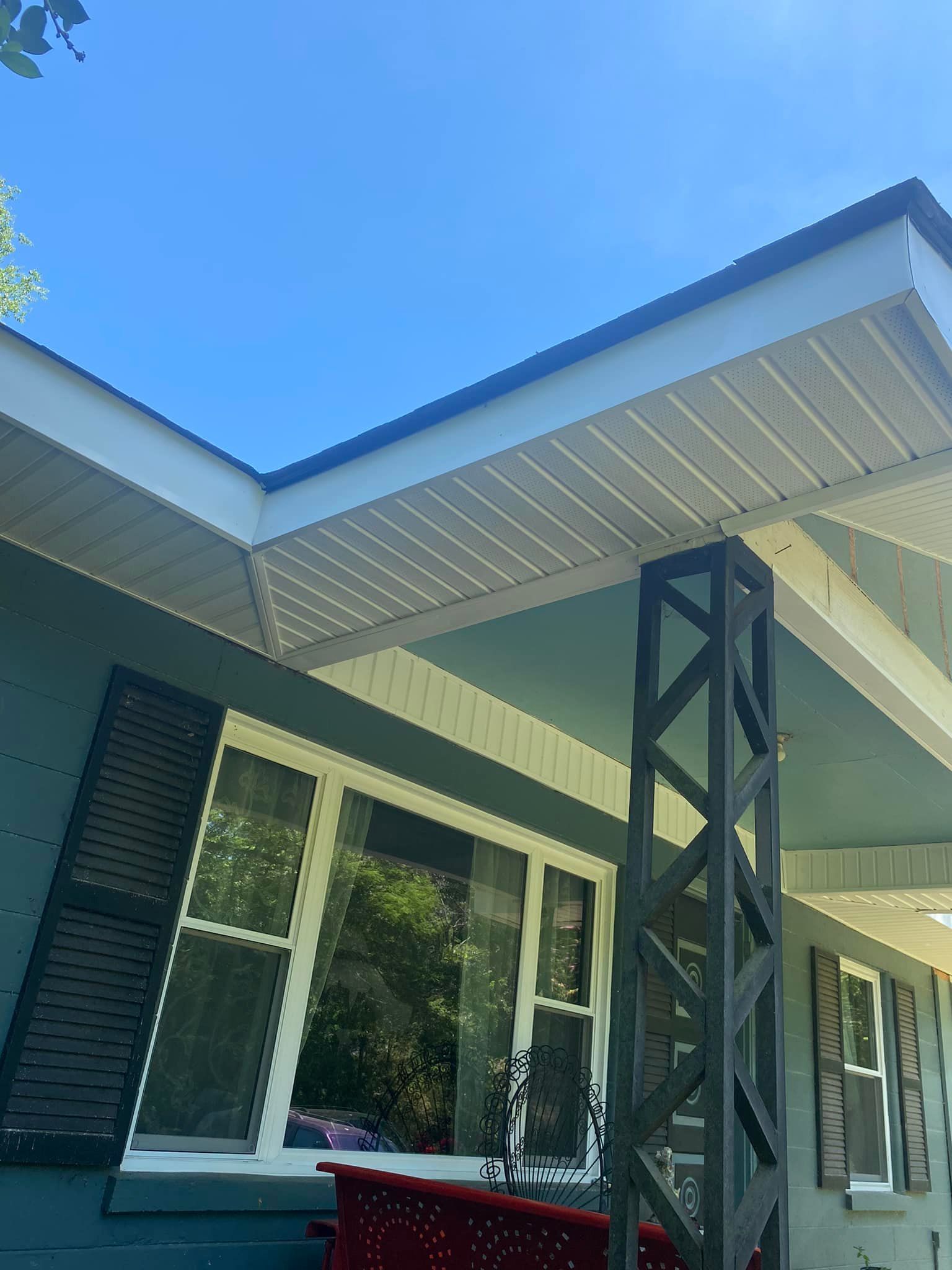 Blue house exterior with white trim, black shutters and column. Clear blue sky.