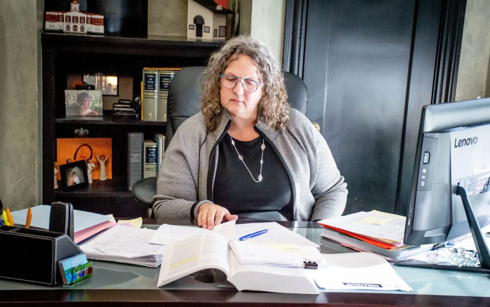 Woman at desk with papers, looking down, in an office setting.