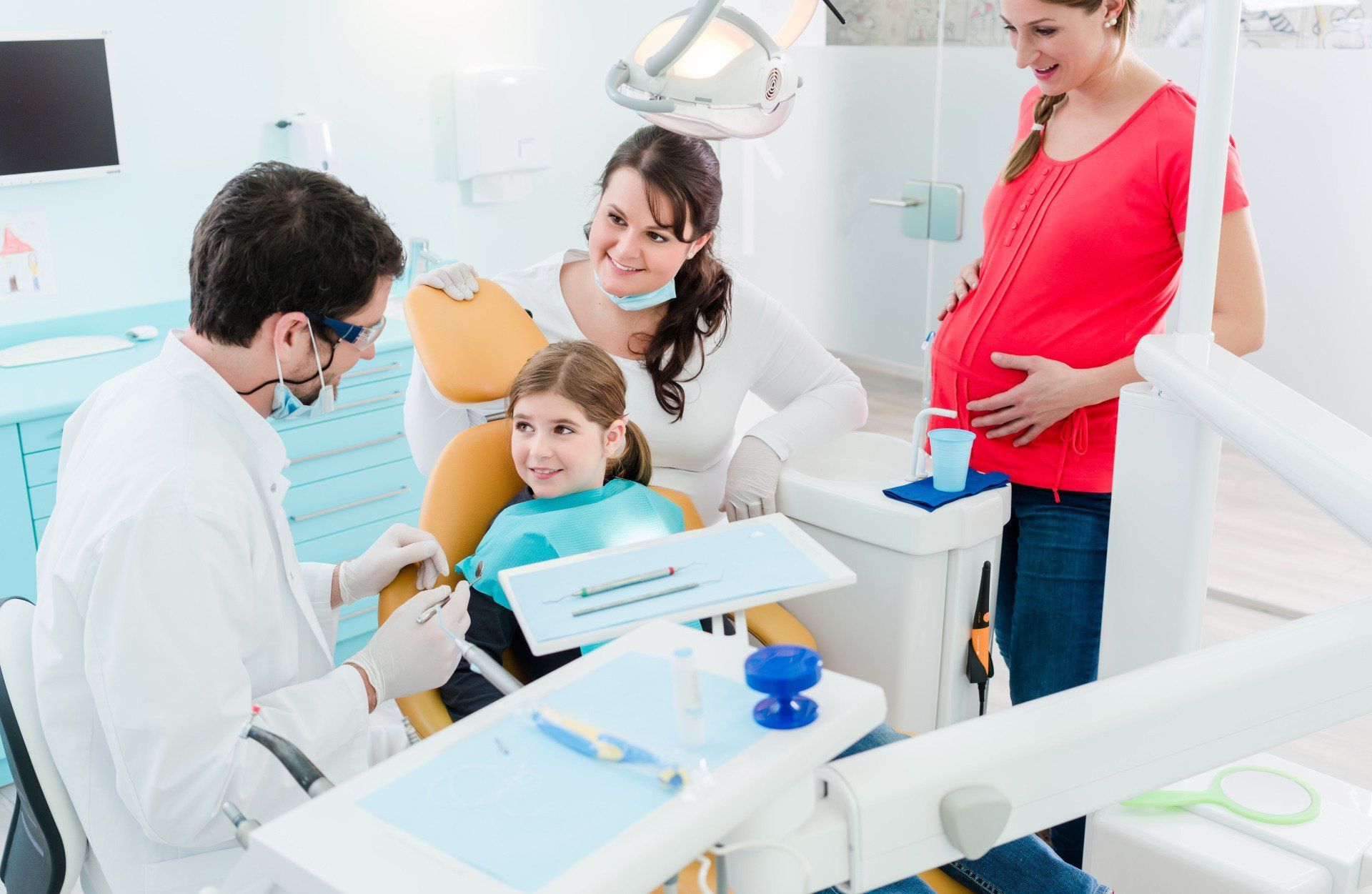 Dentist with patient and family in a bright dental clinic, discussing treatment around the chair