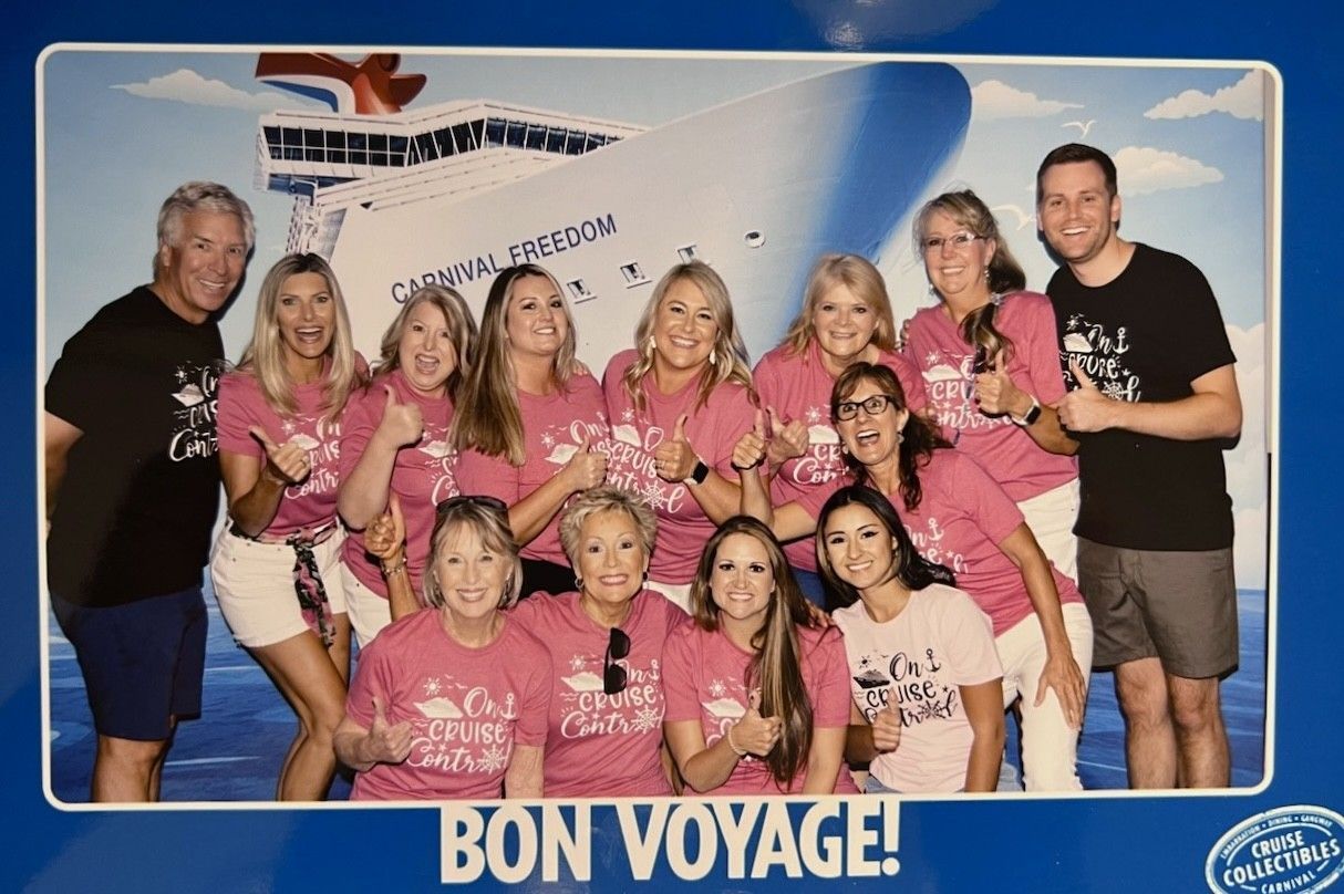 Group of people in pink shirts posing in front of a 
